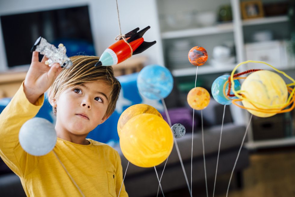 Niño aprendiendo el sistema solar con un modelo de planetas – recursos para aprender inglés sobre el solar system para niños