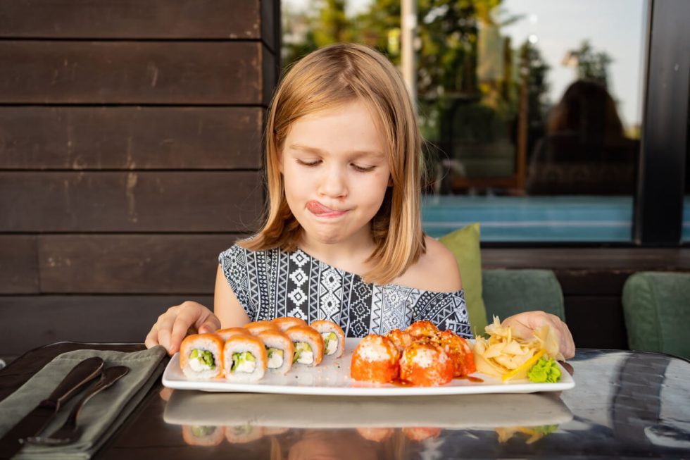 Niña comiendo sushi mientras aprende vocabulario de comida en inglés para niños