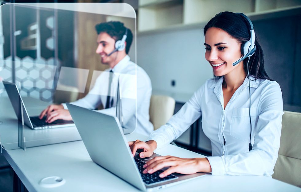Profesional atendiendo una llamada con auriculares mientras habla por teléfono en inglés durante una reunión de trabajo online.